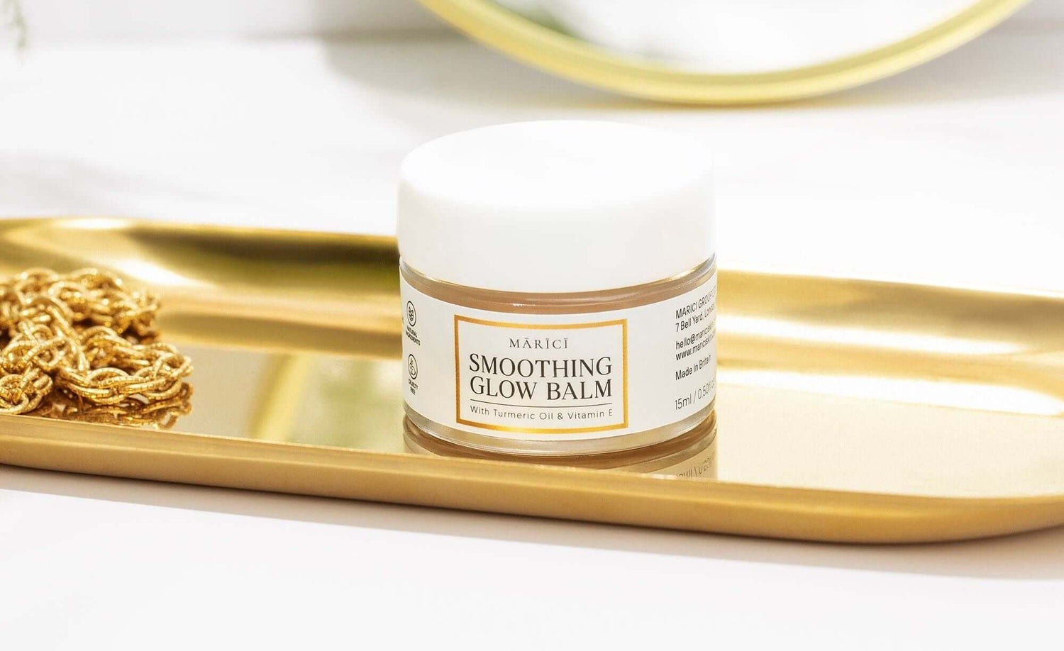 MAKICI Smoothing Glow Balm jar on a gold tray, featuring turmeric oil and vitamin E for radiant skin.